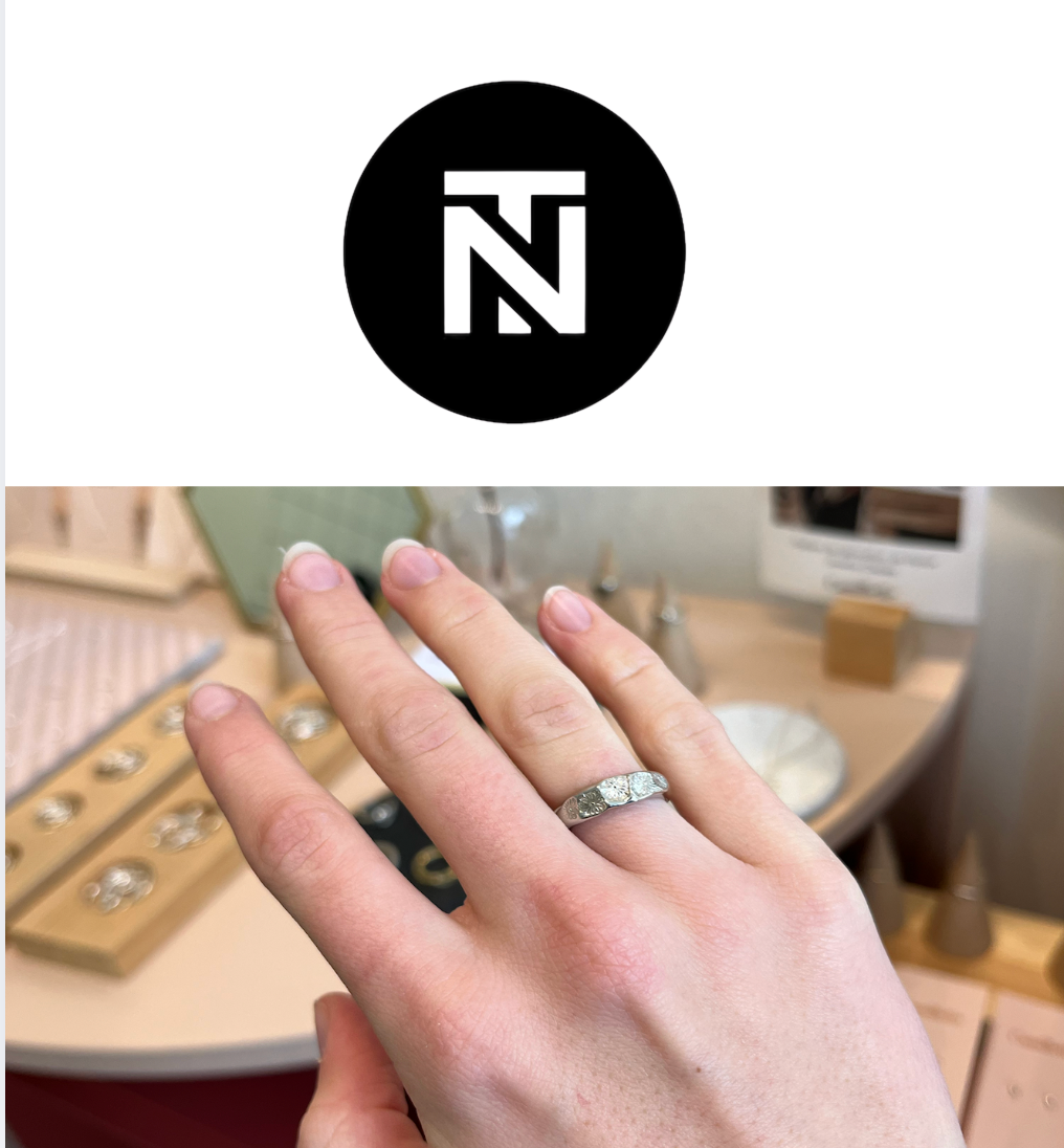 Hand wearing a ring with a jewelry store setting in the background