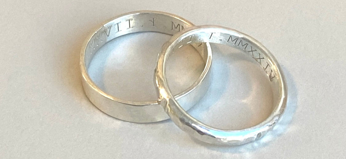 Two silver rings with engraved text on a light gray background
